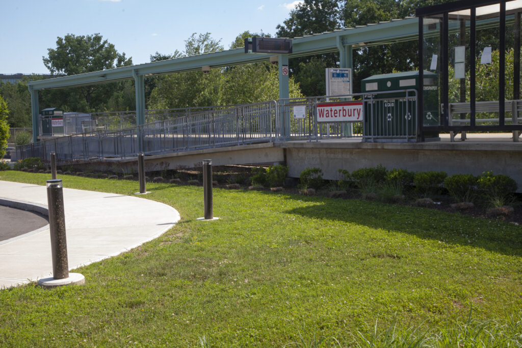 Pedestrian ramp at the Waterbury Station platform. Image includes sidewalks leading the the ramp and a landscape photo of the platform.